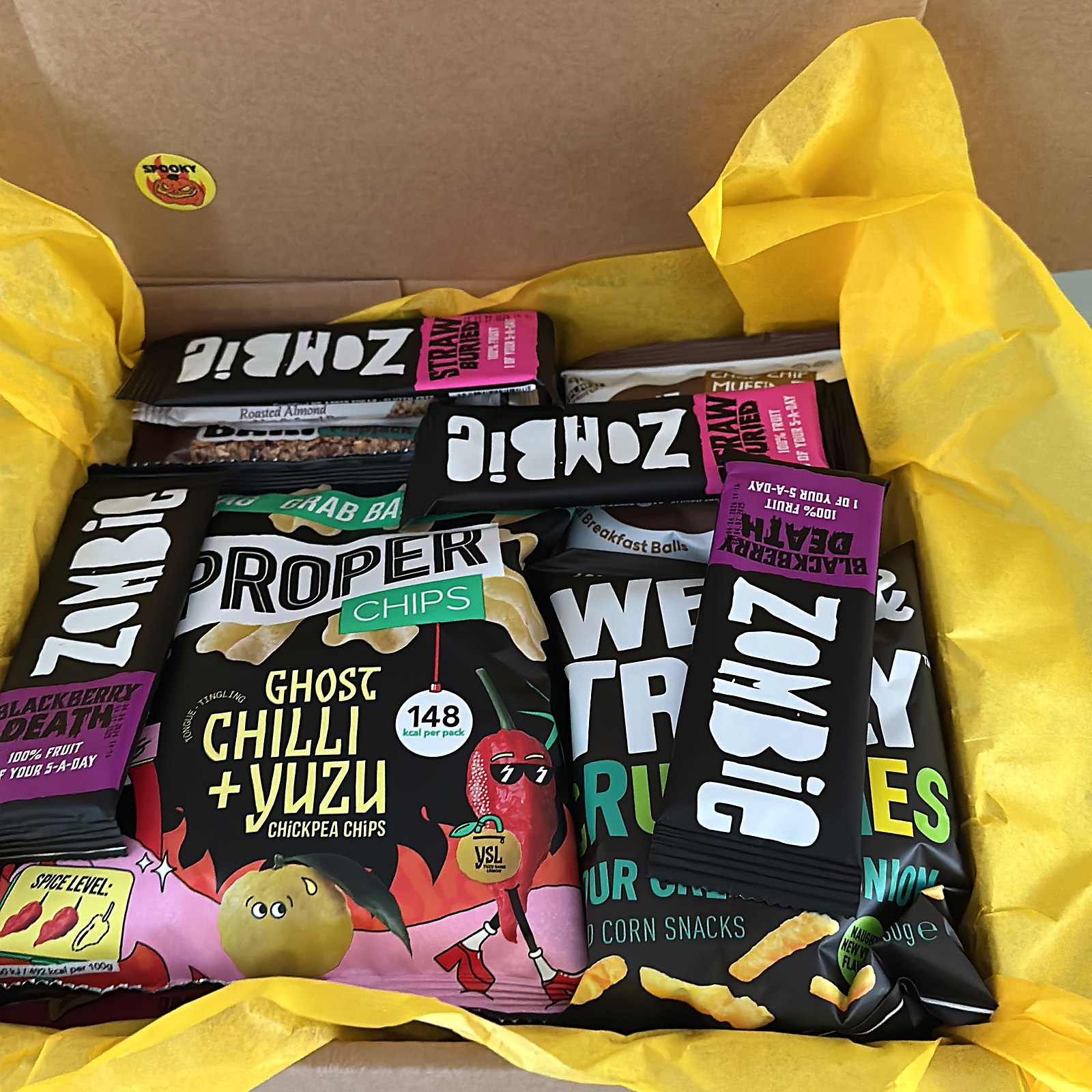 Treat Trunk Halloween vegan snack box, open and packed with Zombie fruit bars, Proper Chips and yellow tissue paper